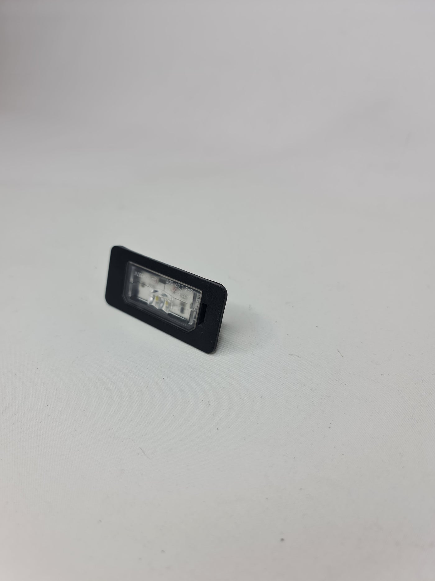 BMW LED license plate light for 2006-2020 models, part number 63267193293, illuminated license plate light in close-up view.