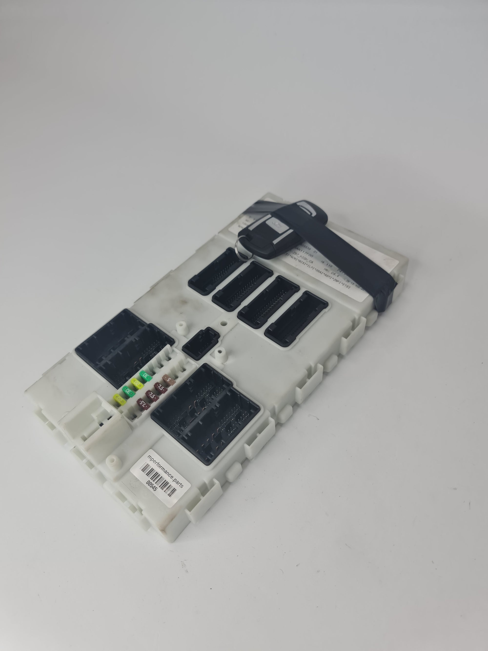 F80 M3 Body Control Comfort Module BCM with key, showing the black module and attached wiring for vehicle control systems