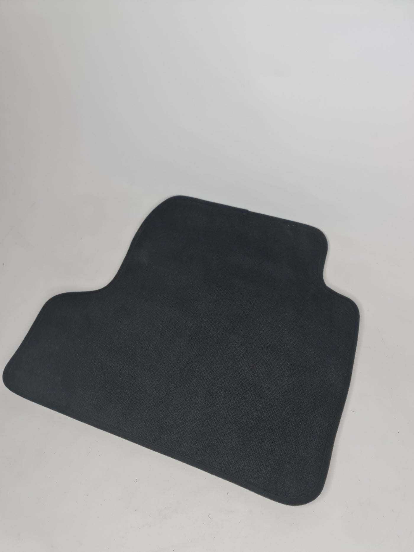 MPerformance.parts F82 M4 rear left floor mat showing textured black rubber surface and custom fit shape for vehicle interior.