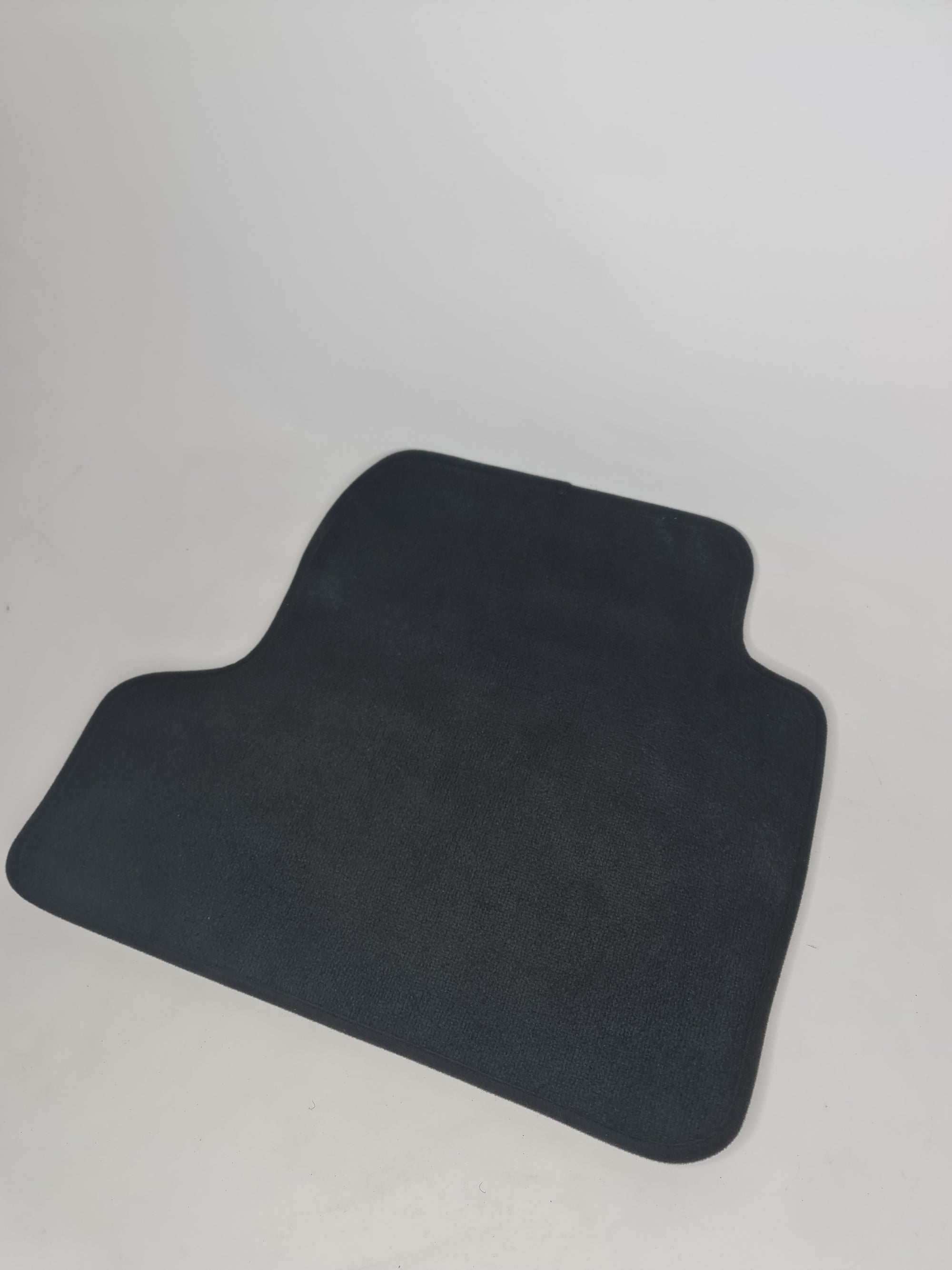 MPerformance.parts F82 M4 rear left floor mat showing textured black rubber surface and custom fit shape for vehicle interior.