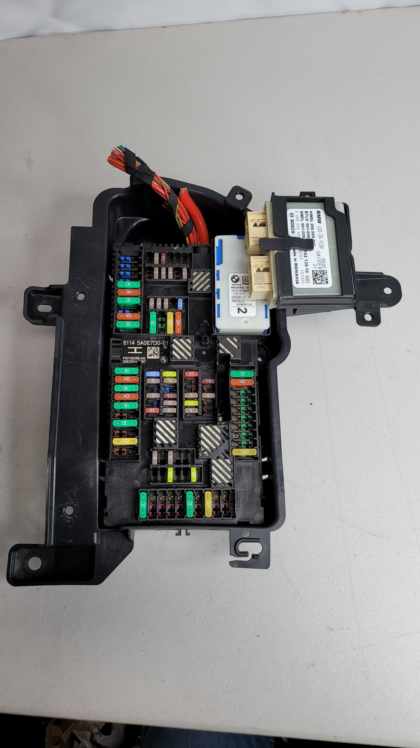 BMW M4 rear trunk power distribution fuse box, part 5A0E7D0, with visible fuse slots and wiring for engine compartment.