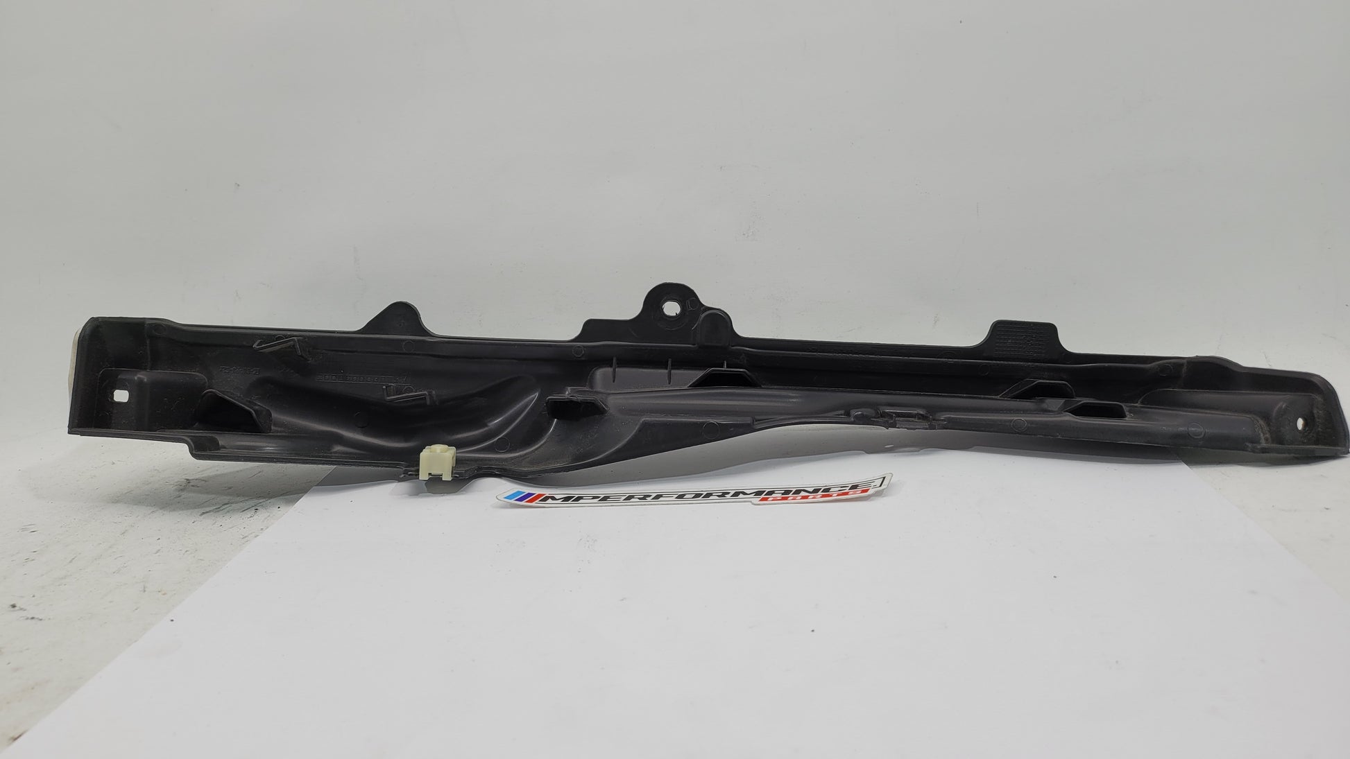 BMW M3 G8x engine compartment panel by MPerformance.parts, showing the black metal panel with mounting holes and branding details.