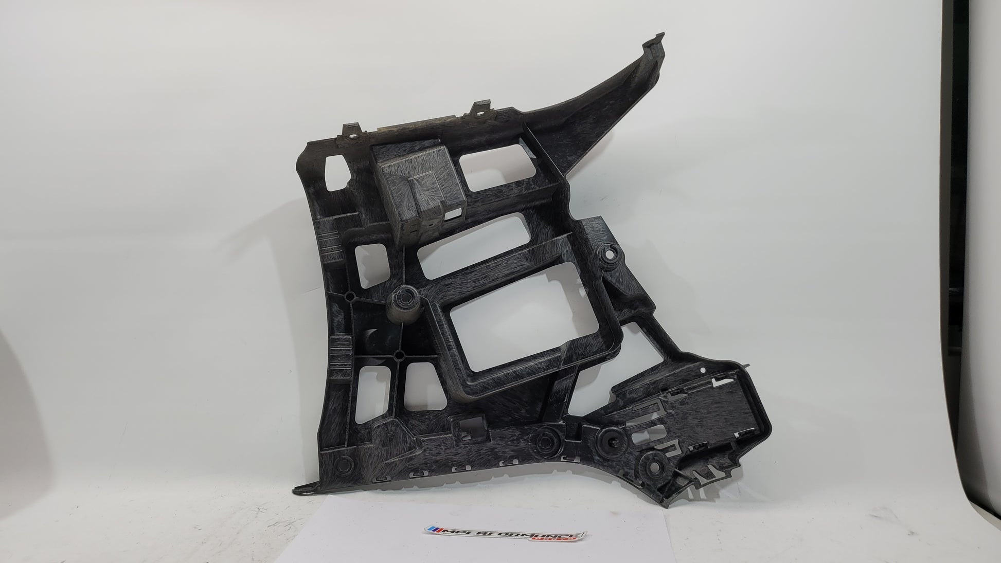 BMW G80 M3 rear left bumper holder bracket by MPerformance.parts, showing the black metal mounting bracket with mounting holes.