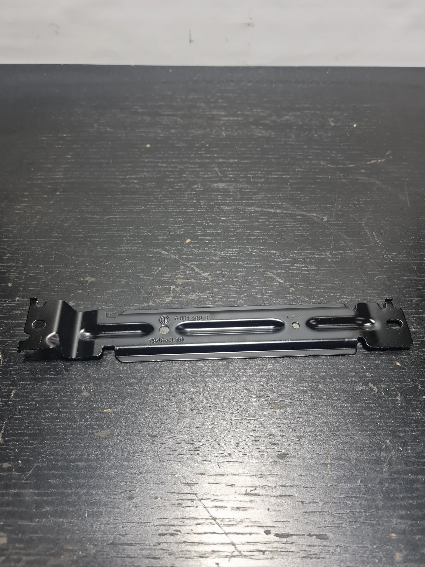 BMW 3 Series G20 battery hold down clamp by MPerformance.parts, shown in black with metal components for secure battery mounting.