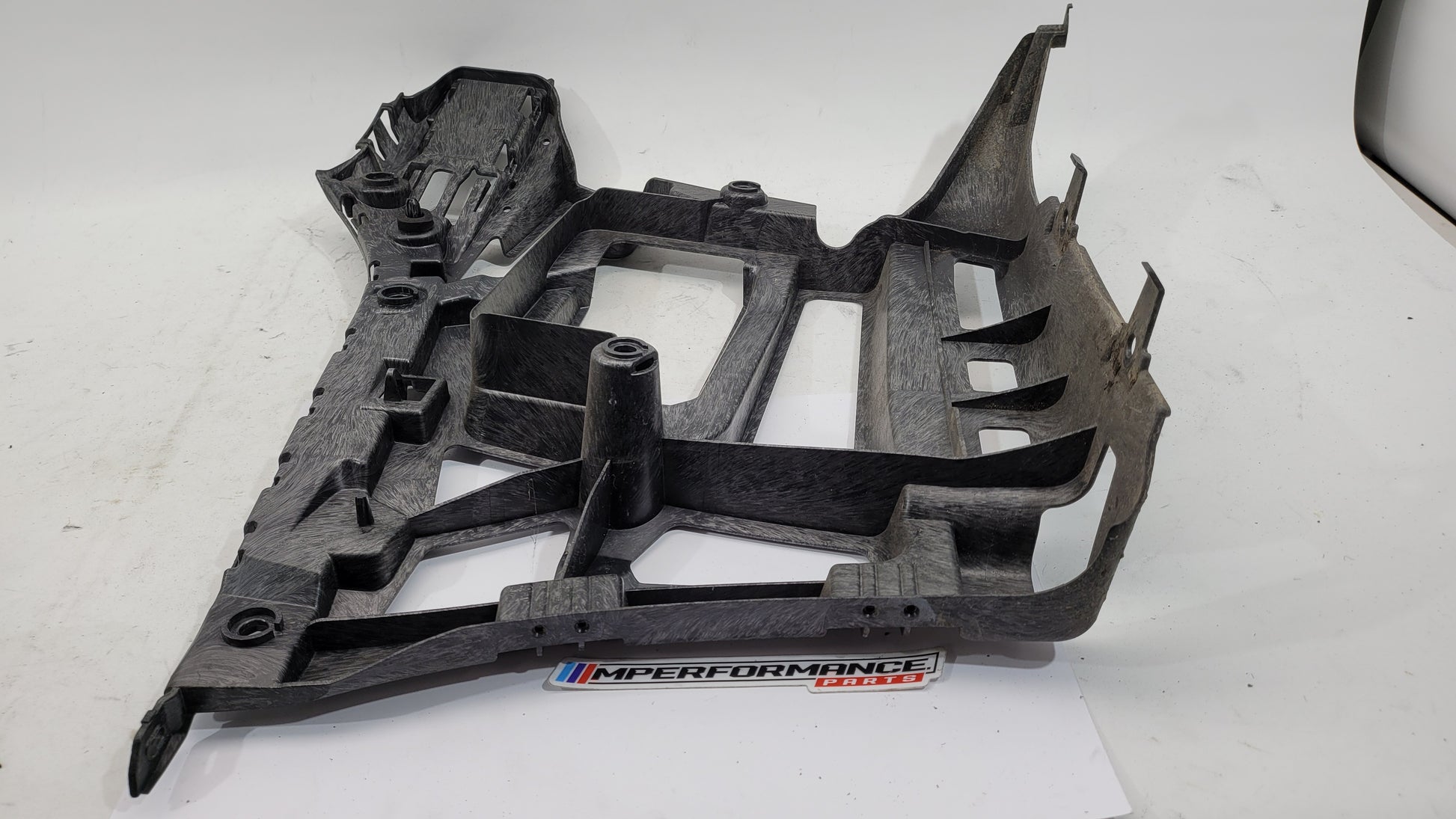 BMW M3 xDrive G80 rear bumper support bracket showing a metal mounting component with bolt holes.