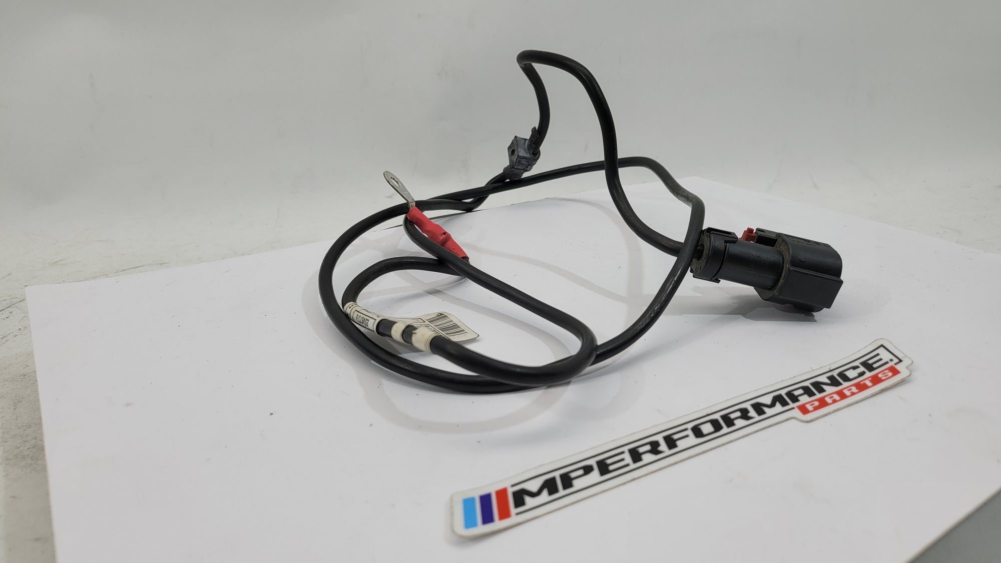 BMW F83 M4 positive battery power distribution cable from MPerformance.parts, showing the heavy-duty cable with connectors and insulation.