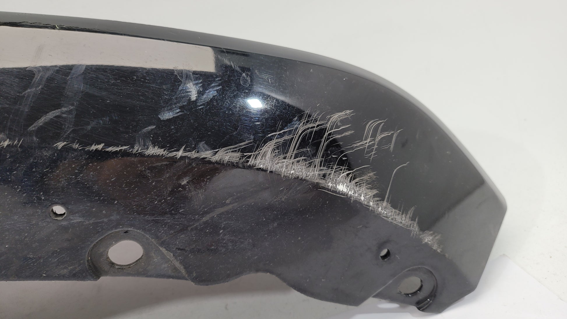 BMW G80 M3 rear bumper left corner spat splitter by MPerformance.parts, showing the black plastic aerodynamic part with mounting points.
